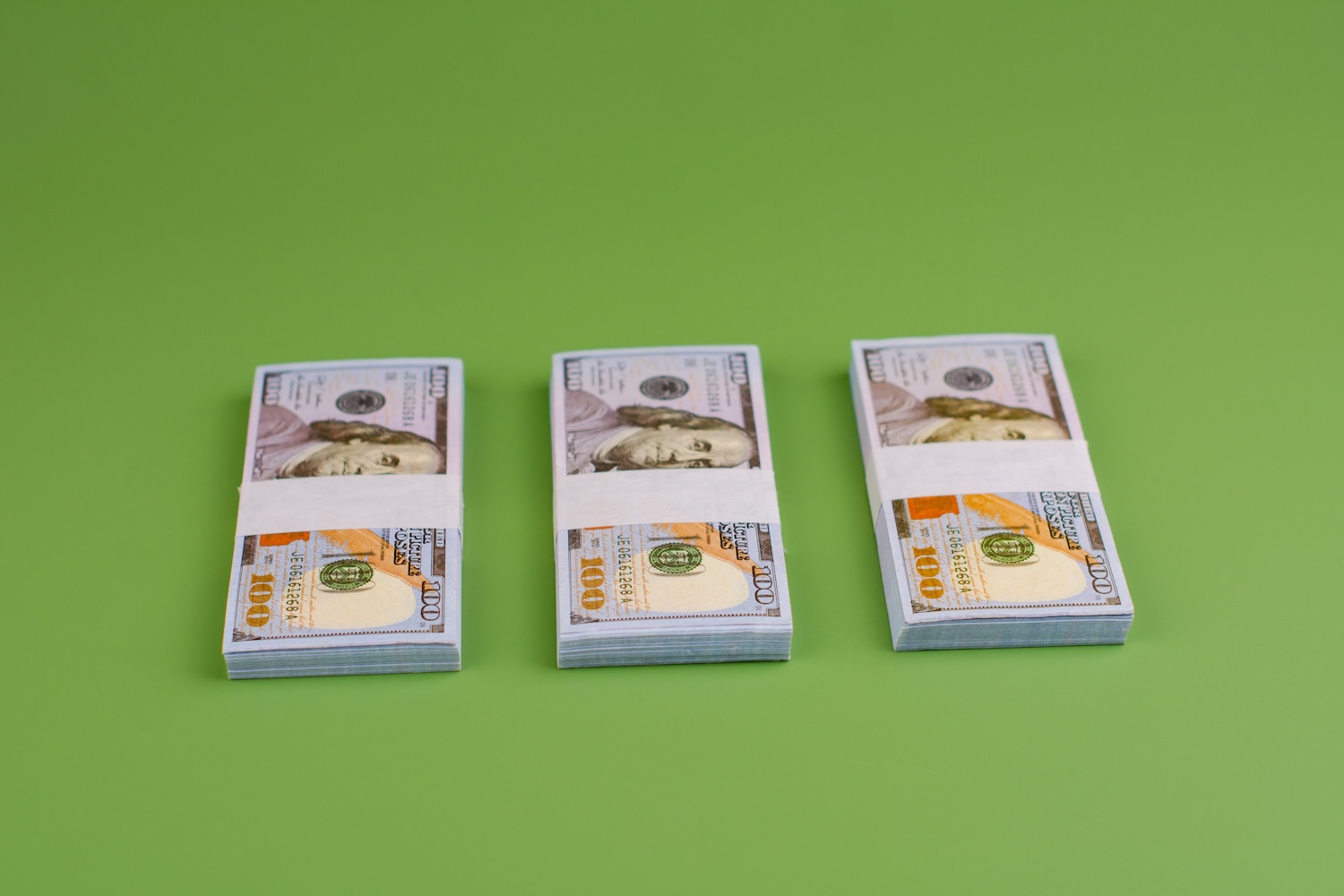 Three piles of dollars to represent ‘Can You Take Out More Than One Personal Loan?’