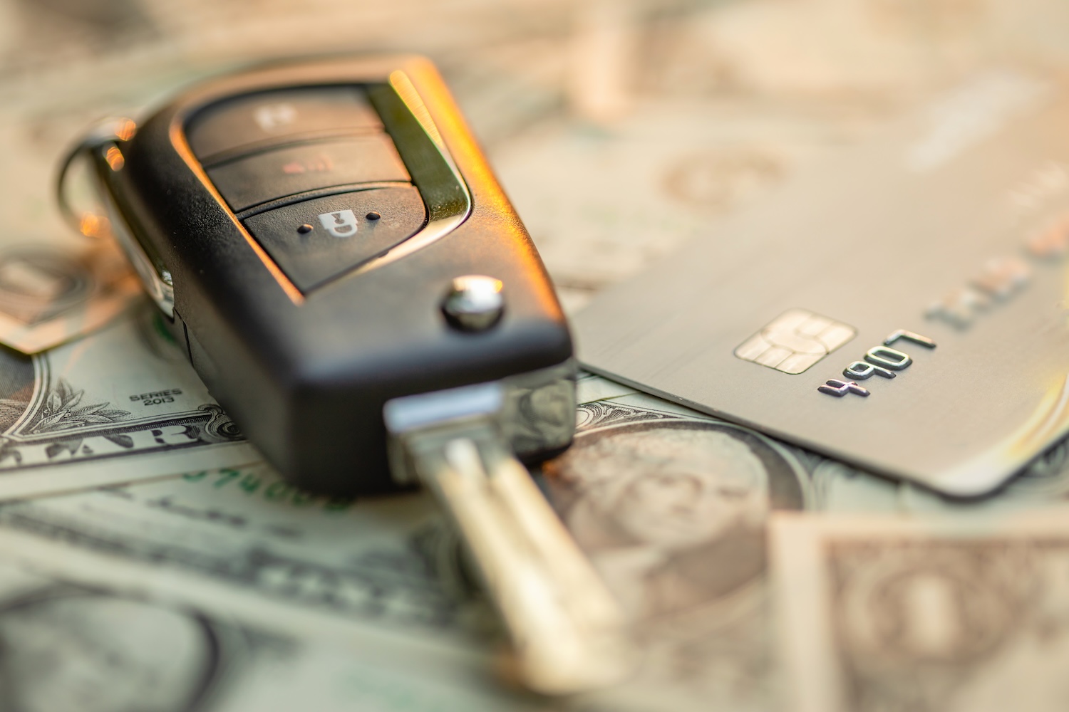 Close up new car keys, credit card and US dollar banknote on wooden table. To represent 'What can be used as collateral for a personal loan?'