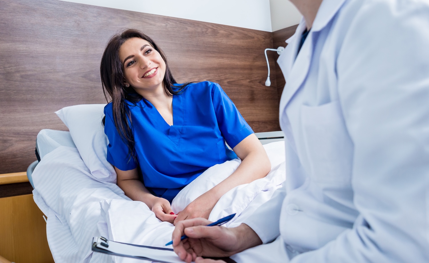 Traumatologist talking with young female patient in modern hospital.
