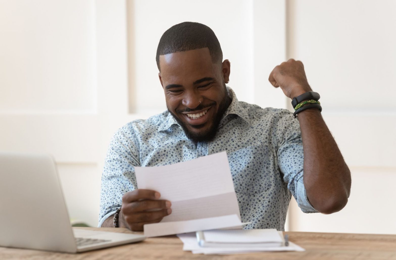 A black man looking at a piece of paper, celebrating because he knows the ways to improve your chances of loan approval