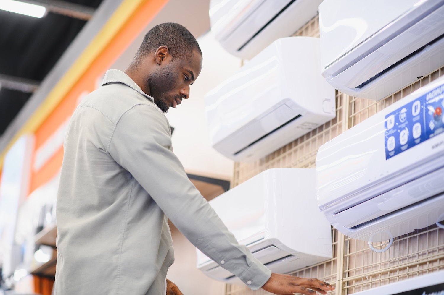A man looking at different air conditioners, thinking about paying for it with air conditioning loans