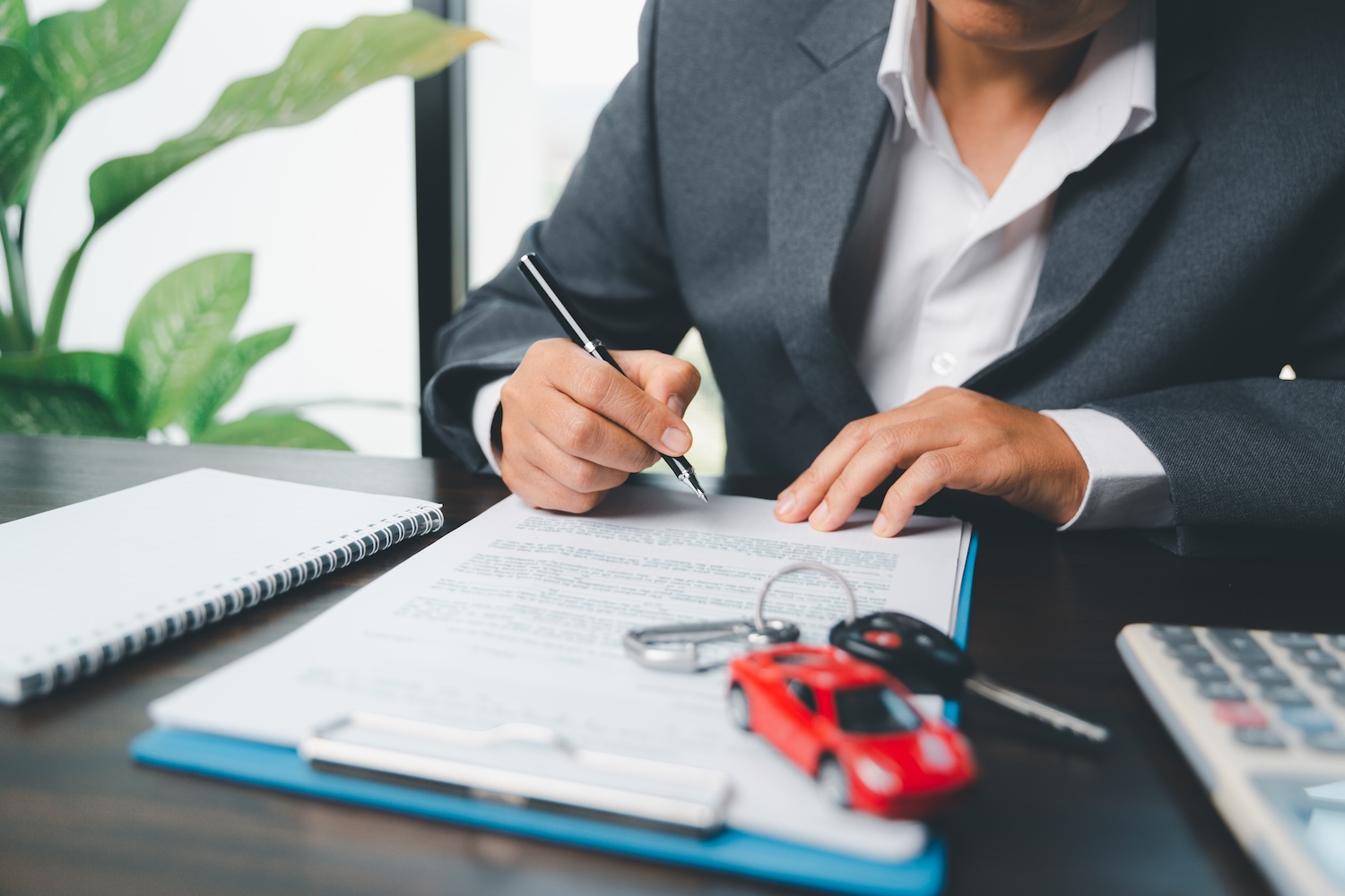 A woman signing an auto local document after they found out whether a personal loan affects your odds of getting a car loan