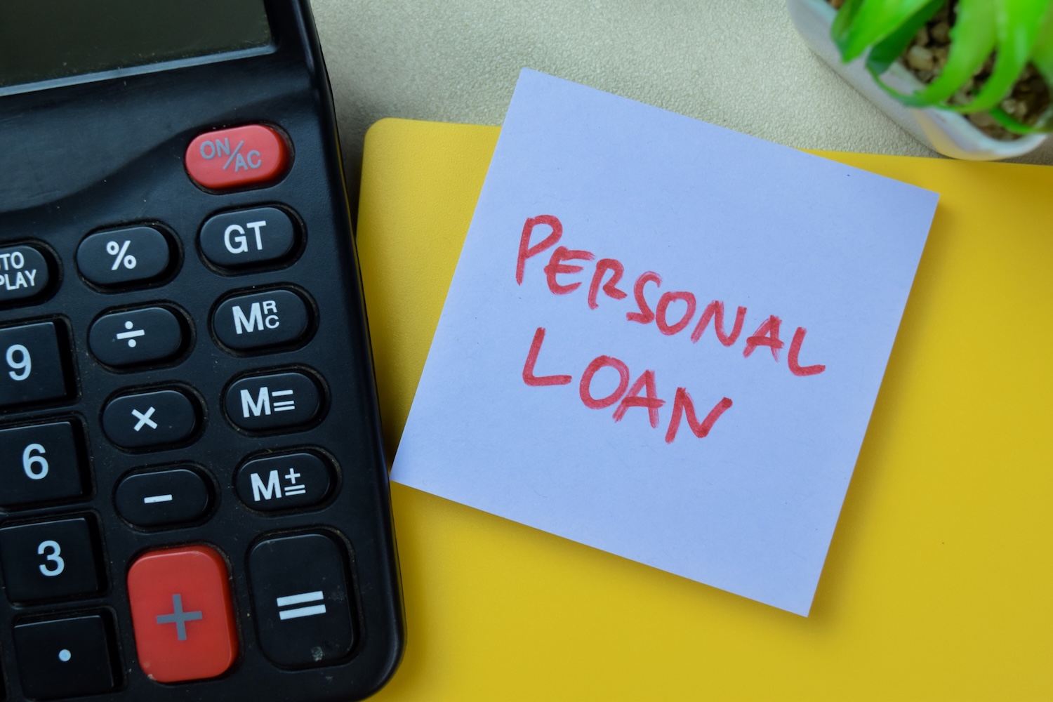 A calculator next to a post-it note that says personal loan to represent how does a personal loan work