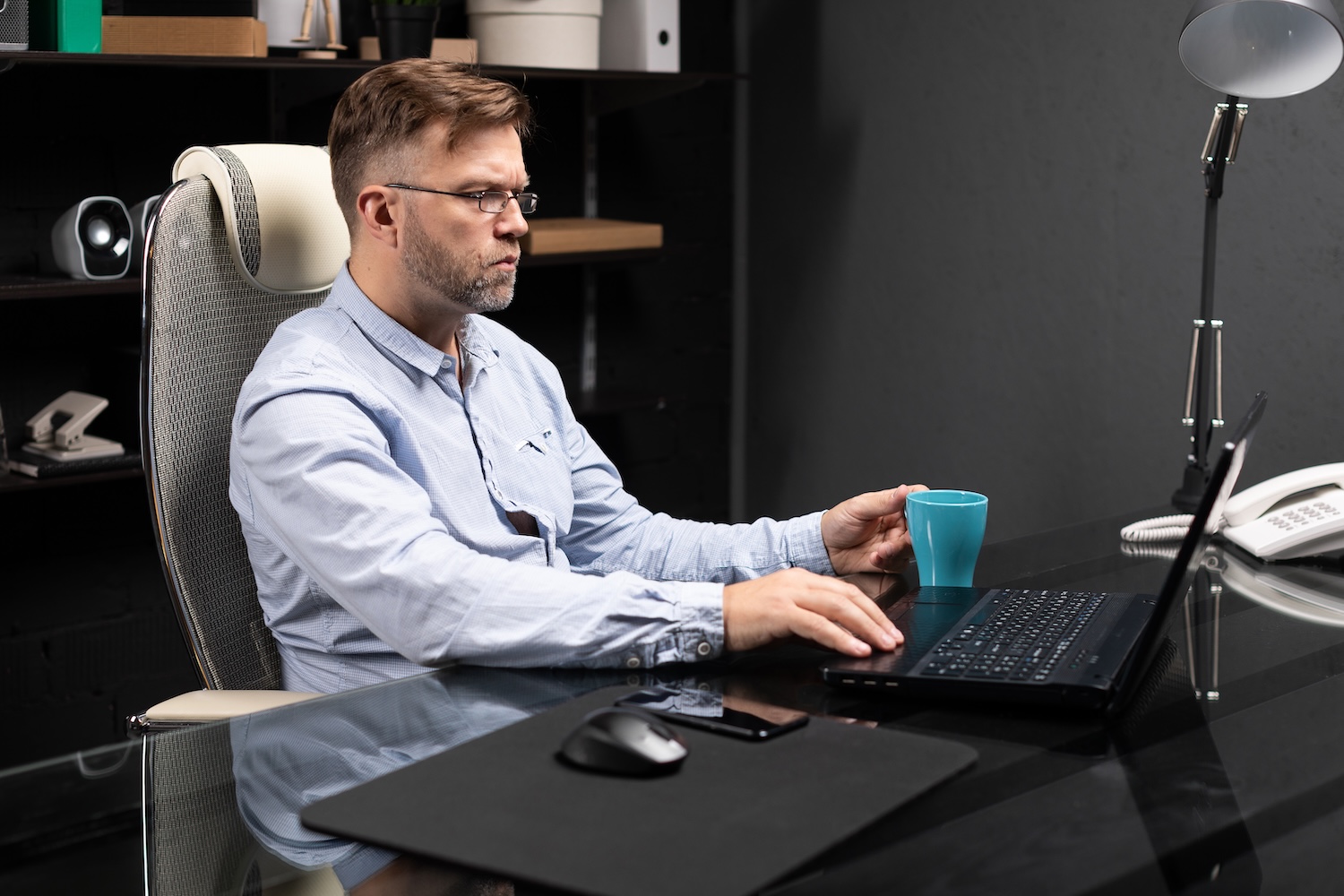 A man working in an office on a laptop he bought with a technology loan
