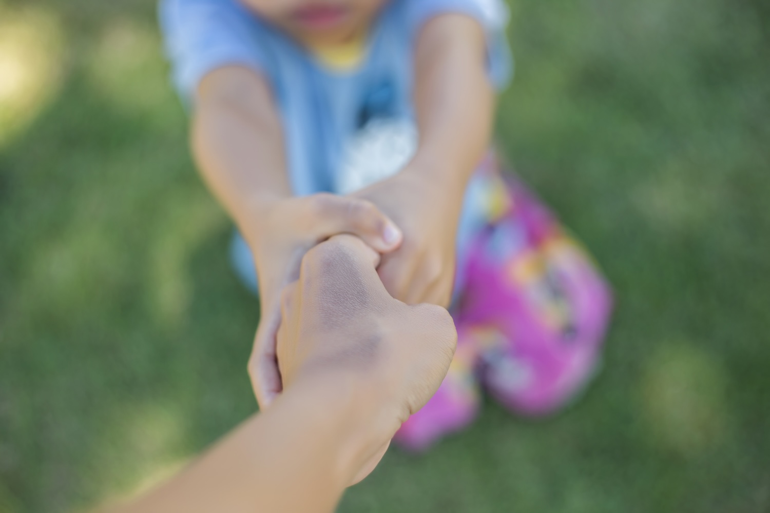 A boy holding their adoptive parents hand