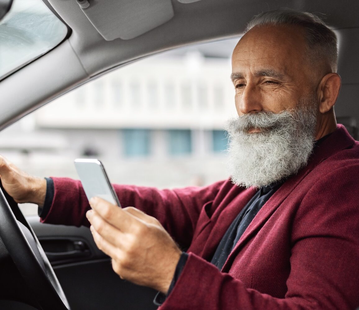 An uber driver looking at his phone in his car